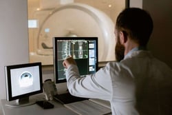 A healthcare professional at a hospital points to a monitor, a piece of medical technology that could be hit by ransomware cyberattacks, learn more in the rest of this White Oak Security blog.
